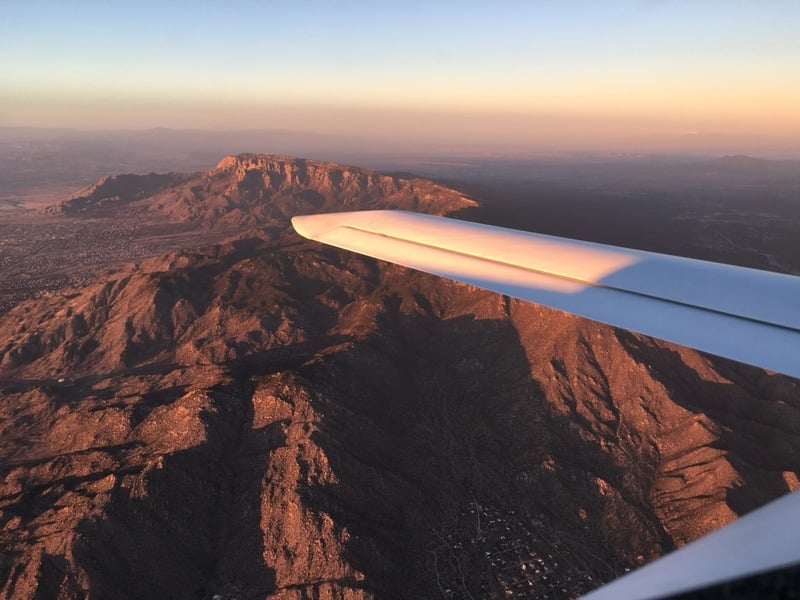 View from airplane wing over mountains at sunset